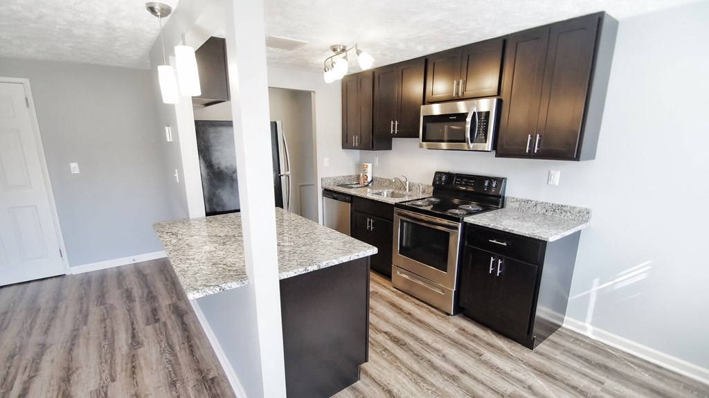 A kitchen with black cabinets and a granite countertop.