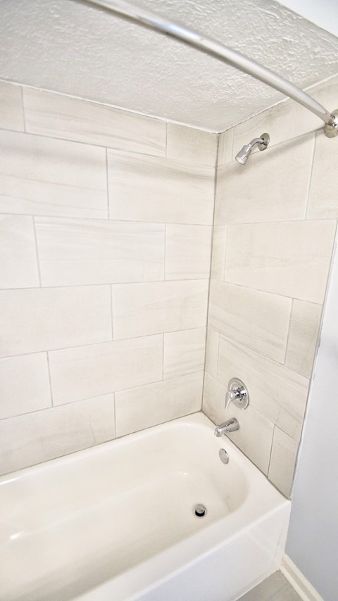 A white bathtub with a shower head and faucet.