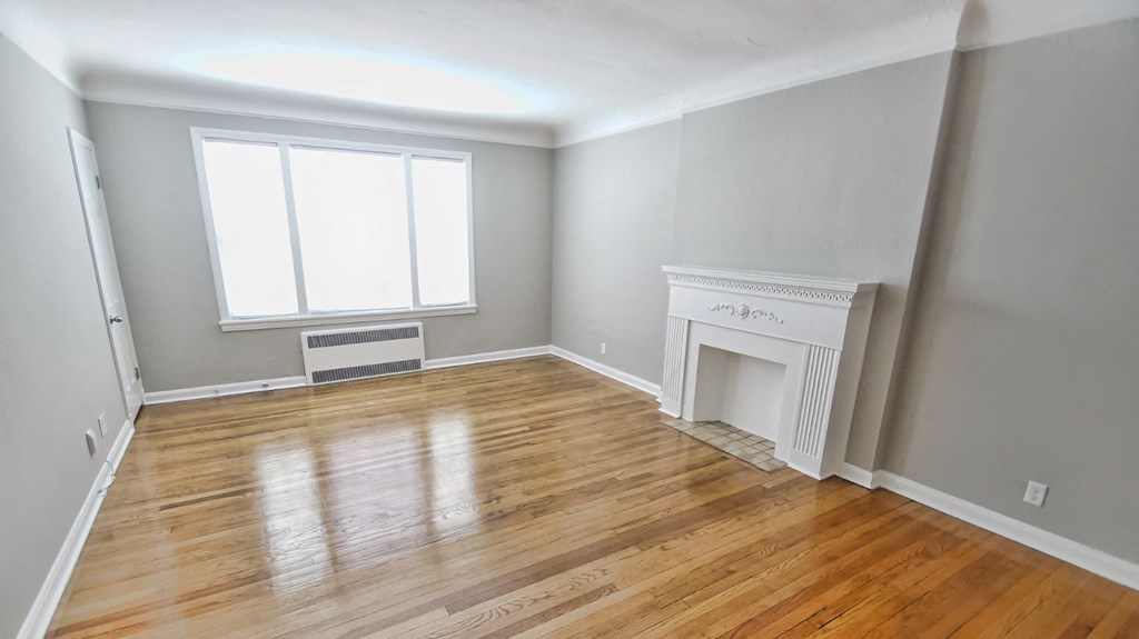 an empty living room with a fireplace and wooden floors