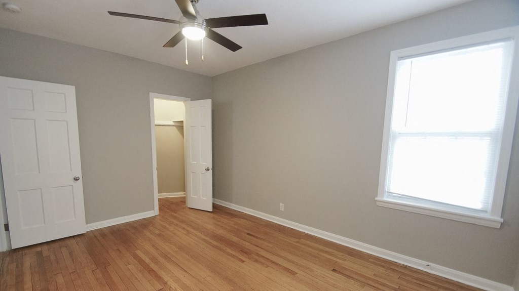 an empty living room with a ceiling fan and a door to a closet