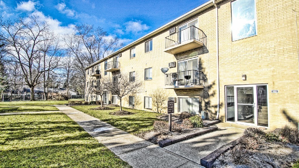 a yellow brick apartment building with a sidewalk and grass