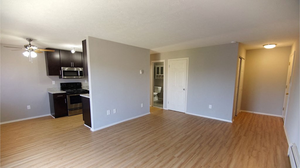 an empty living room and kitchen with wood flooring