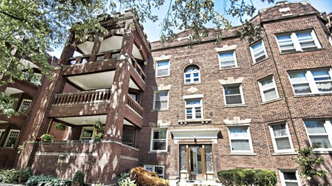 the apartment building has a brick facade and a balcony