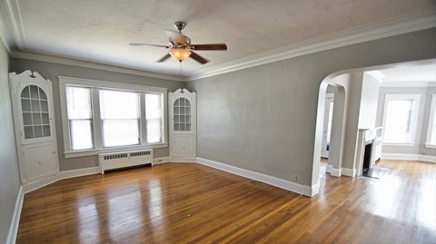 an empty living room with wood floors and a ceiling fan