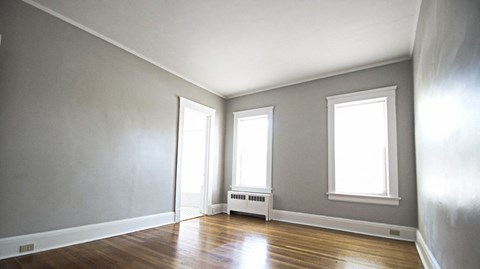an empty room with a wood floor and three windows