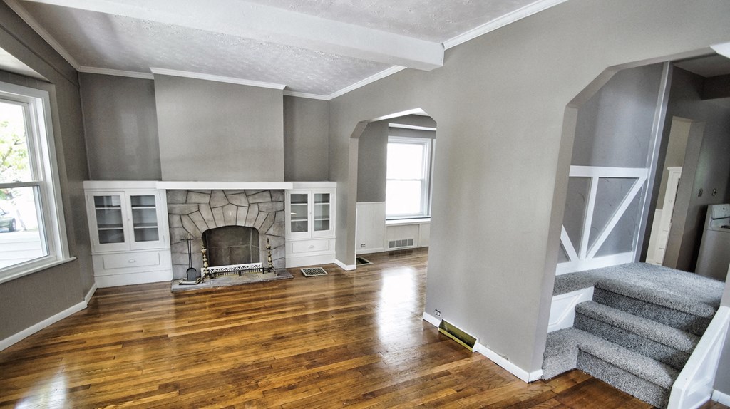 an empty living room with a fireplace and hardwood floors