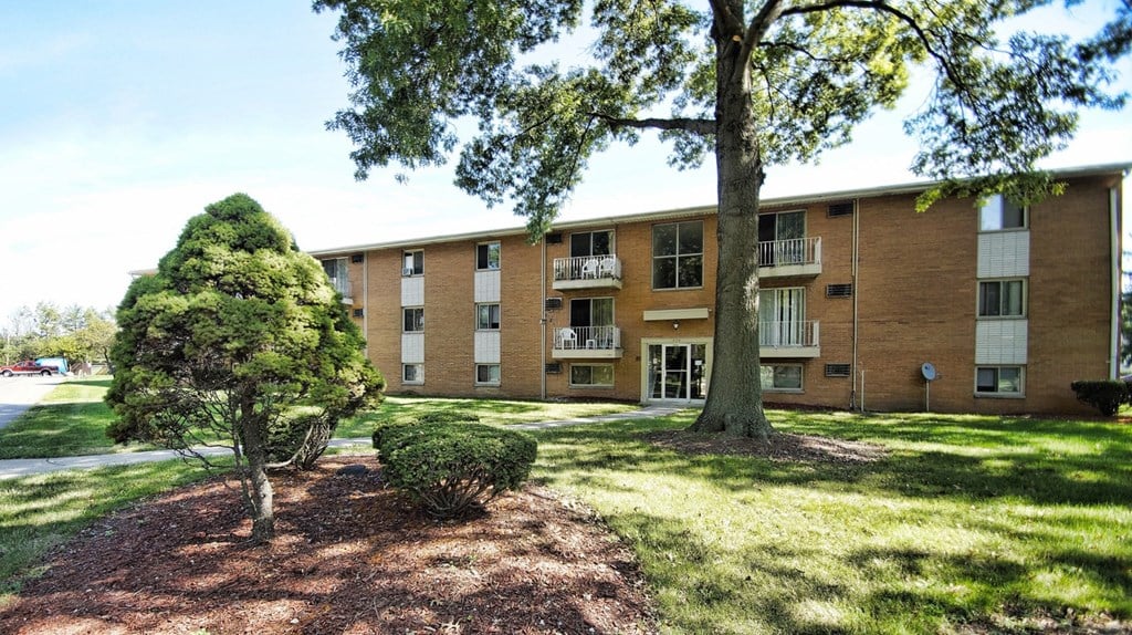 A tree in front of a building with a lawn in between.