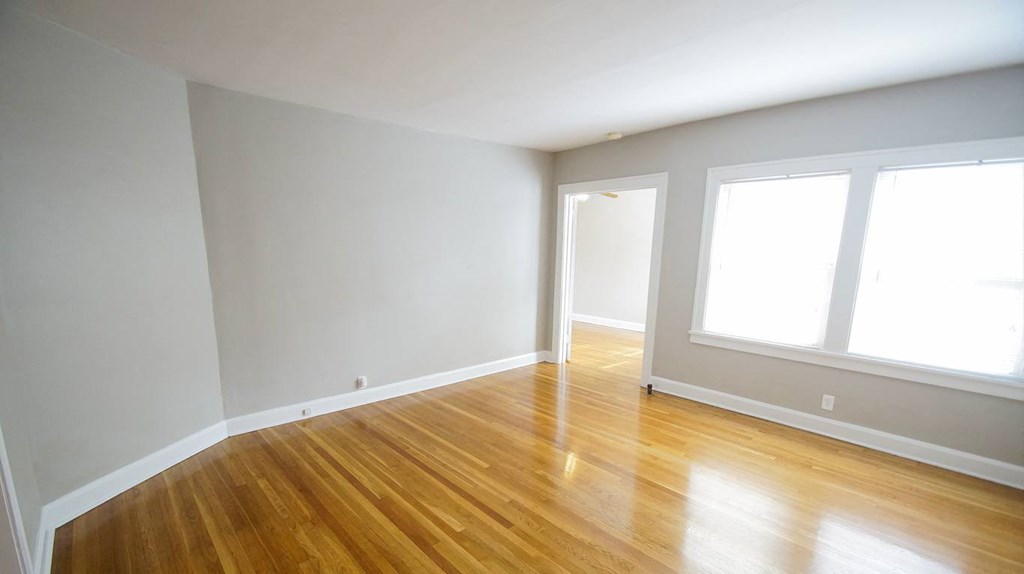an empty room with a hard wood floor and large windows