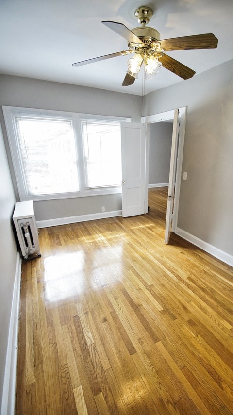 an empty living room with wood floors and a ceiling fan