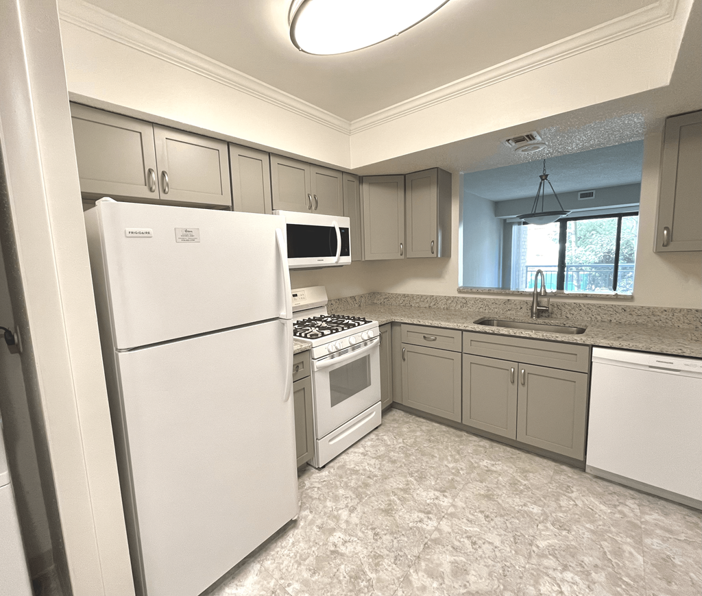 A kitchen with white appliances and grey cabinets.at Atrium in The Village, Beachwood, OH 44122