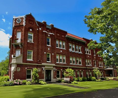 A red brick building with a green lawn in front.
