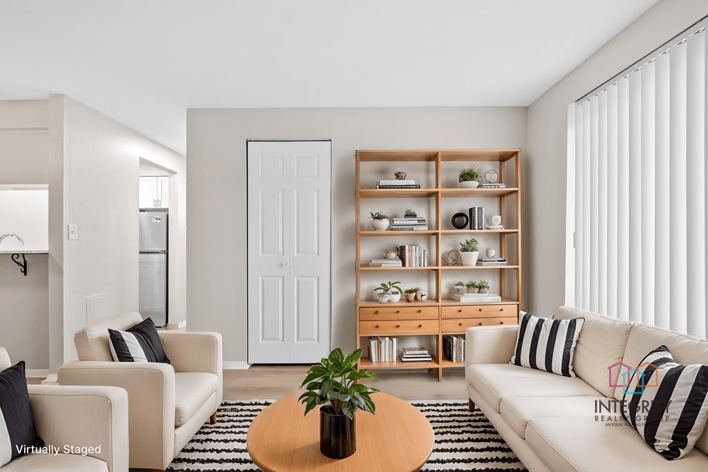 A living room with a white couch, a wooden coffee table, and a white door.