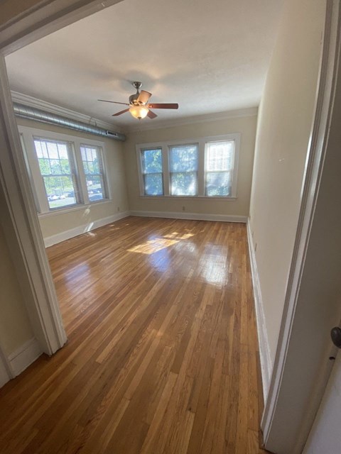 an empty living room with wood floors and a ceiling fan