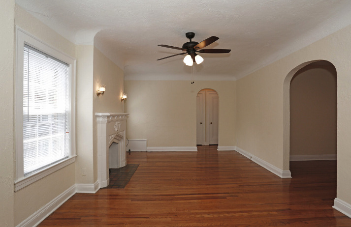 an empty living room with a ceiling fan and a window