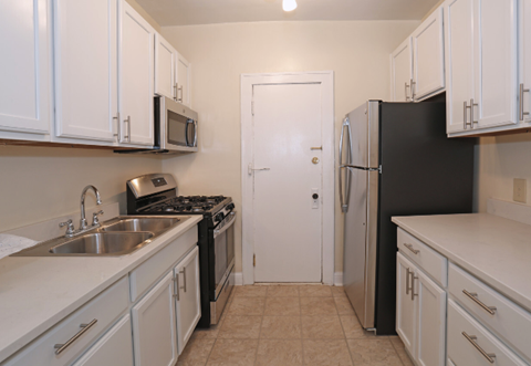 a kitchen with white cabinets and a black refrigerator and a sink