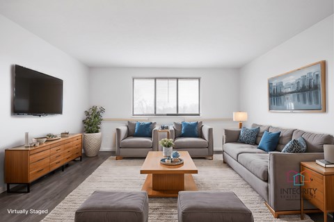 A living room with a grey couch, a brown coffee table, and a flat screen TV mounted on the wall.