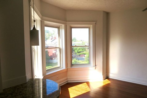 A sunny room with a large window and a view of a red building outside.