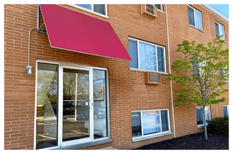 A red awning is attached to a brick building.