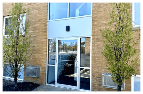 A building with a glass door and two trees on either side.
