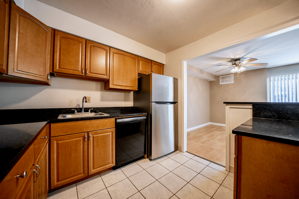 A kitchen with wooden cabinets and a black counter top.