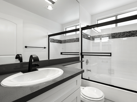 A modern bathroom with a white toilet and a black and white tiled shower.