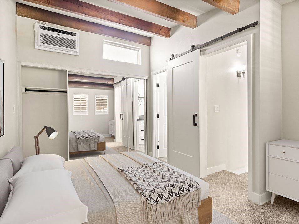 Carpeted bedroom with ceiling fan and access to private bathroom.