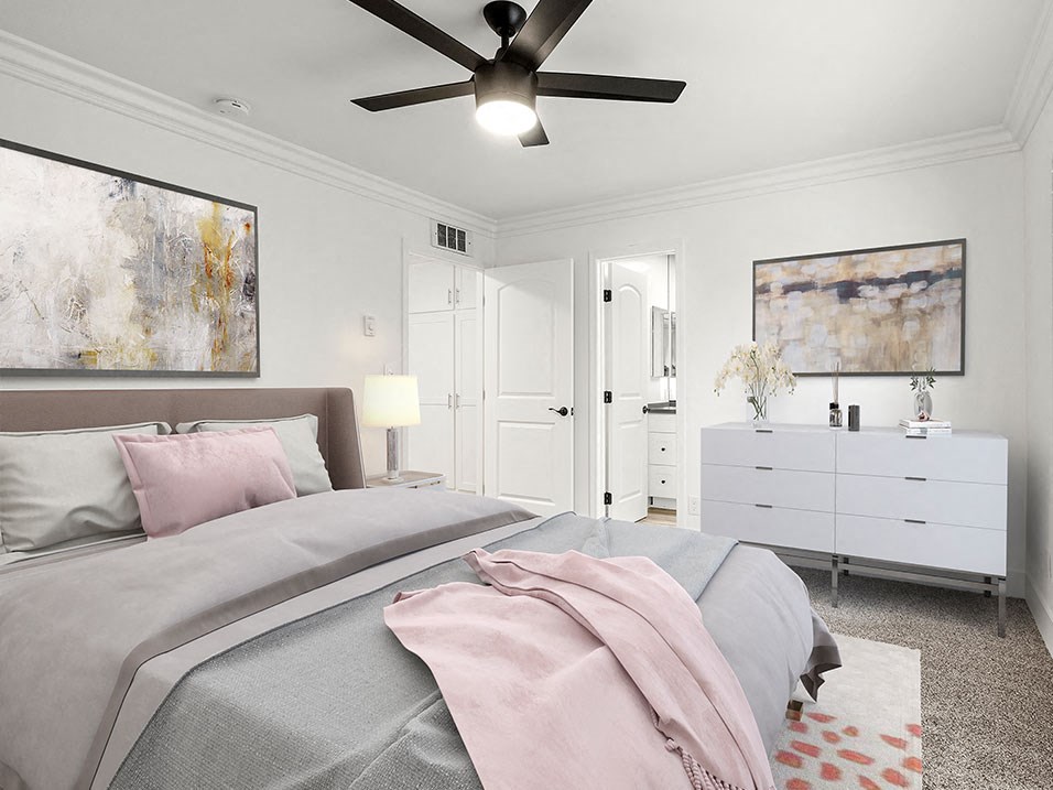 Carpeted bedroom with ceiling fan and access to private bathroom.