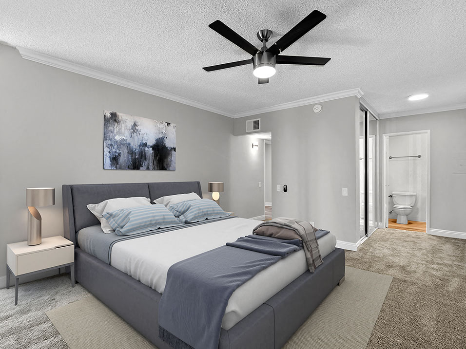 Carpeted bedroom with ceiling fan and private bathroom.