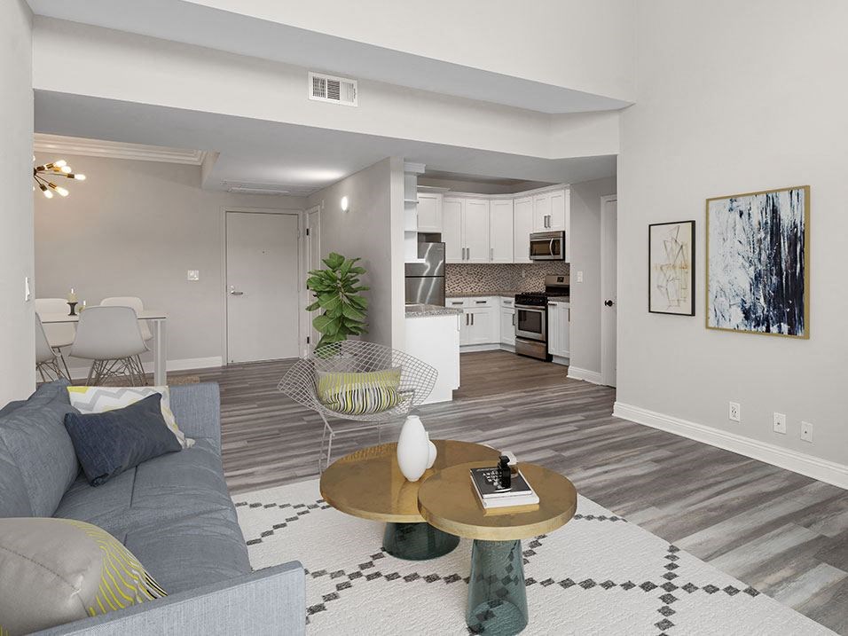 Hardwood floored living room with view of tiled kitchen and dining area.