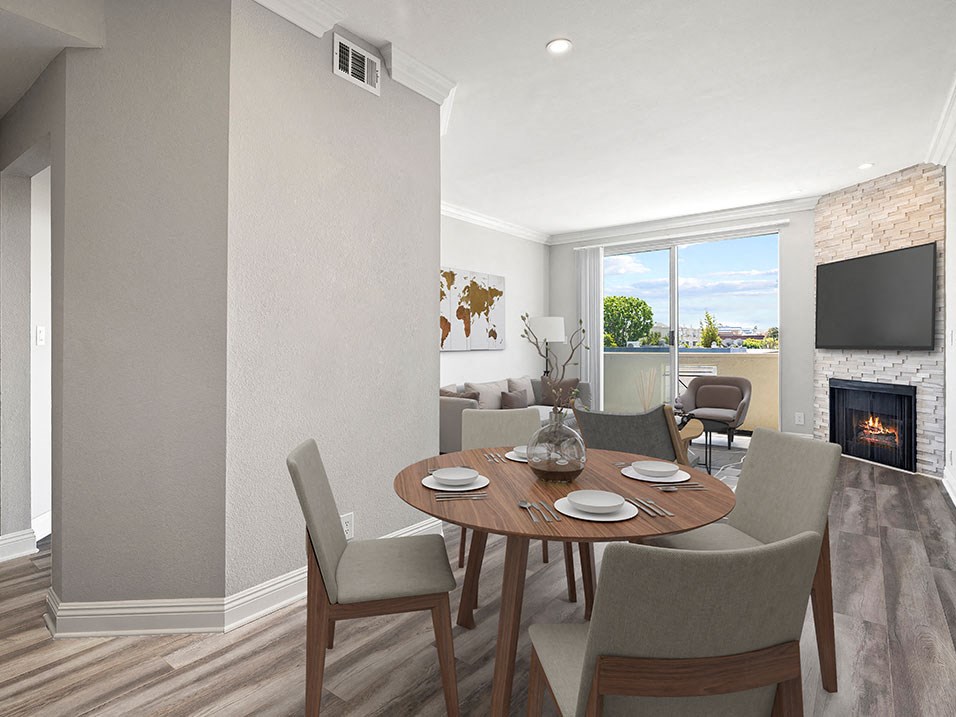 Hardwood floored dining room with view of balcony and stone walled fireplace.