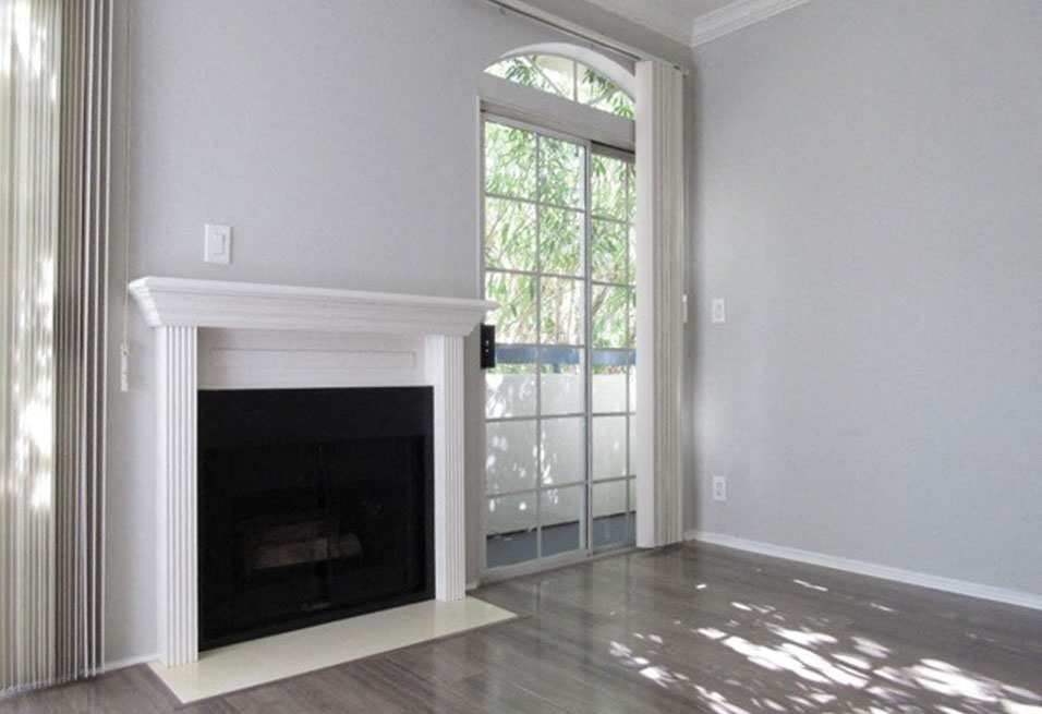 Fireplace with overhanging mantle and large windows with patio access.