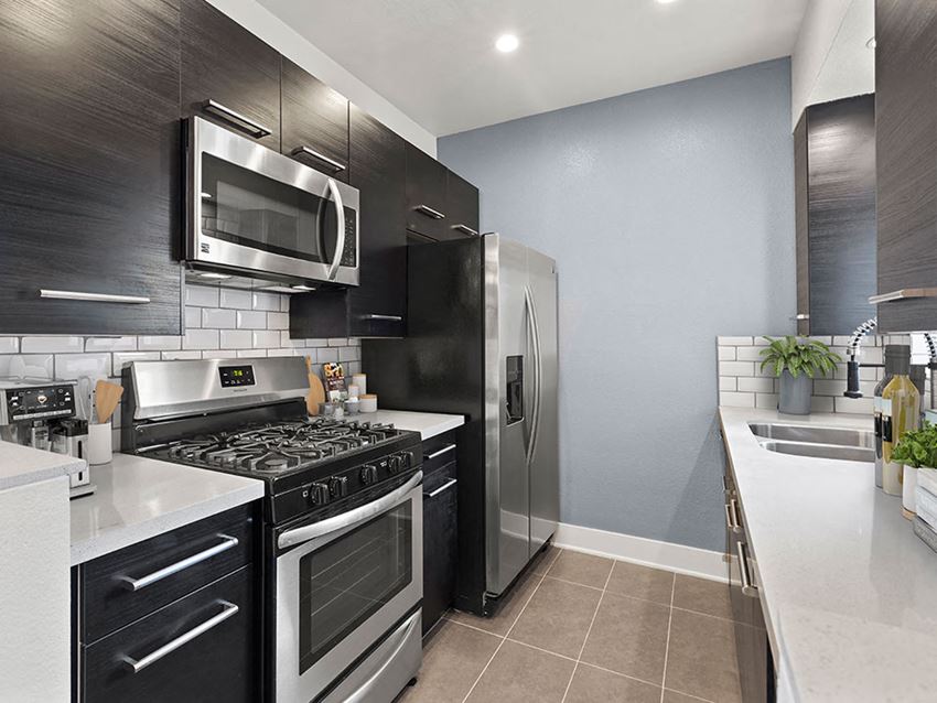White tile kitchen with granite countertop and stainless steel fridge, oven, and fixtures.