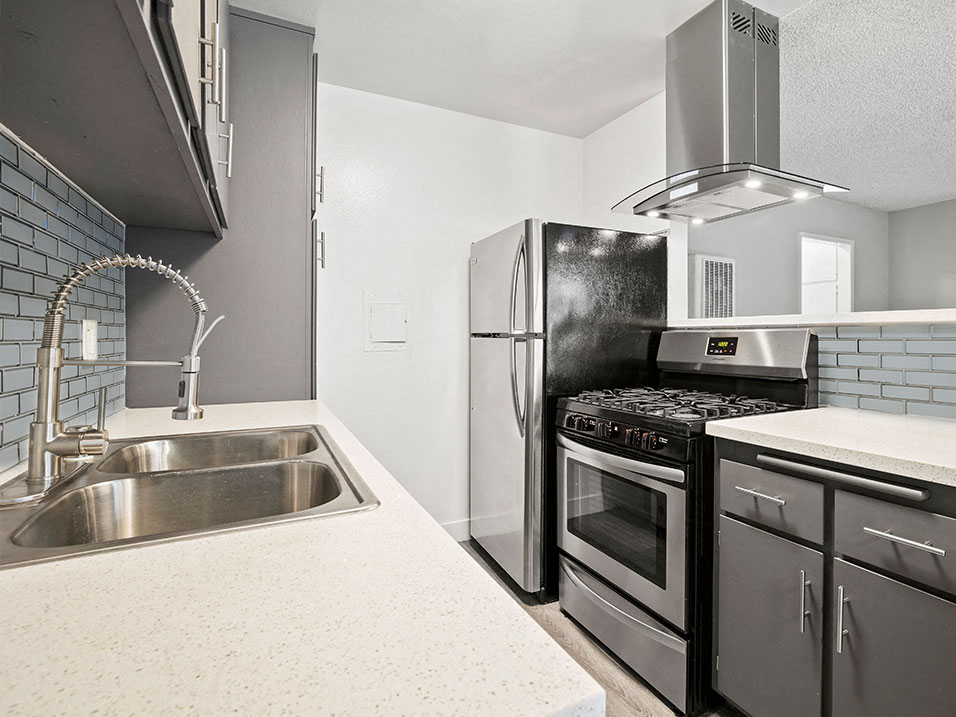 Blue tiled kitchen with stainless steel fridge, oven, and fixtures.