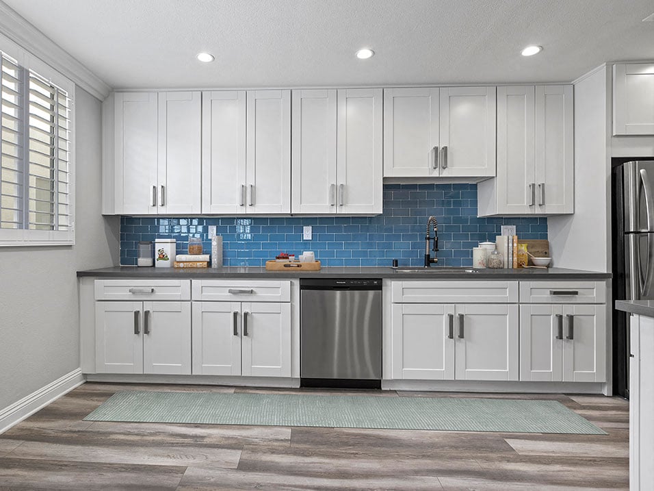 Blue tiled kitchen with stainless steel dishwasher and fixtures.