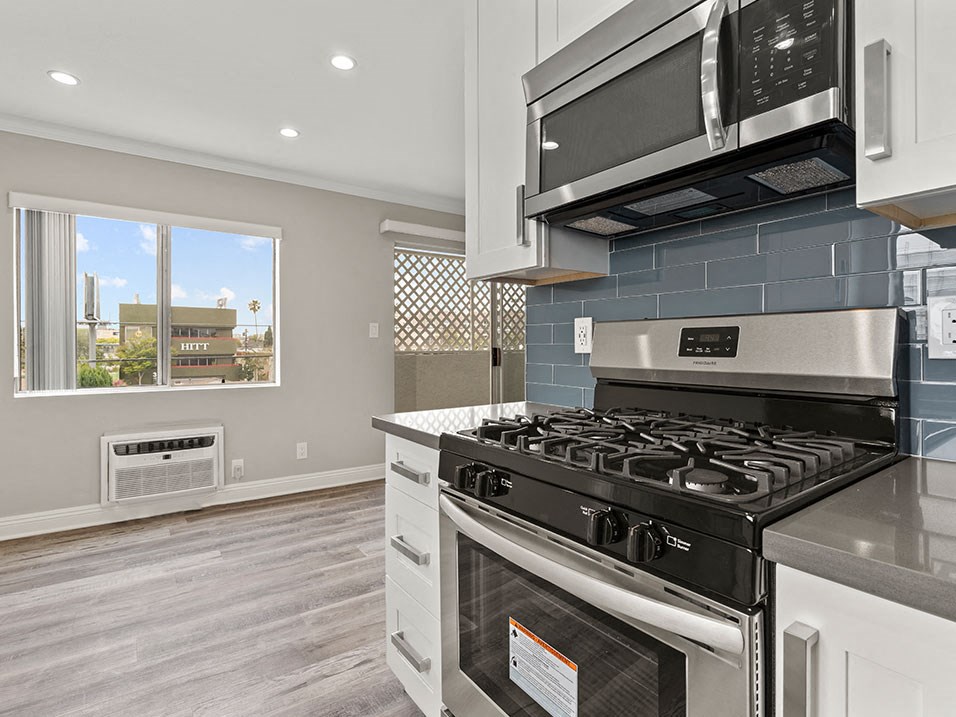 Blue tiled kitchen with stainless steel oven, microwave, and fridge.