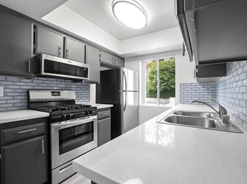 Tiled kitchen with stainless steel oven, microwave, and fridge. Tiled kitchen with stainless steel oven, microwave, and fridge. - Photo Gallery 2