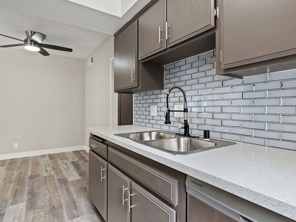 Tiled kitchen with stainless steel sink, microwave, and fridge.