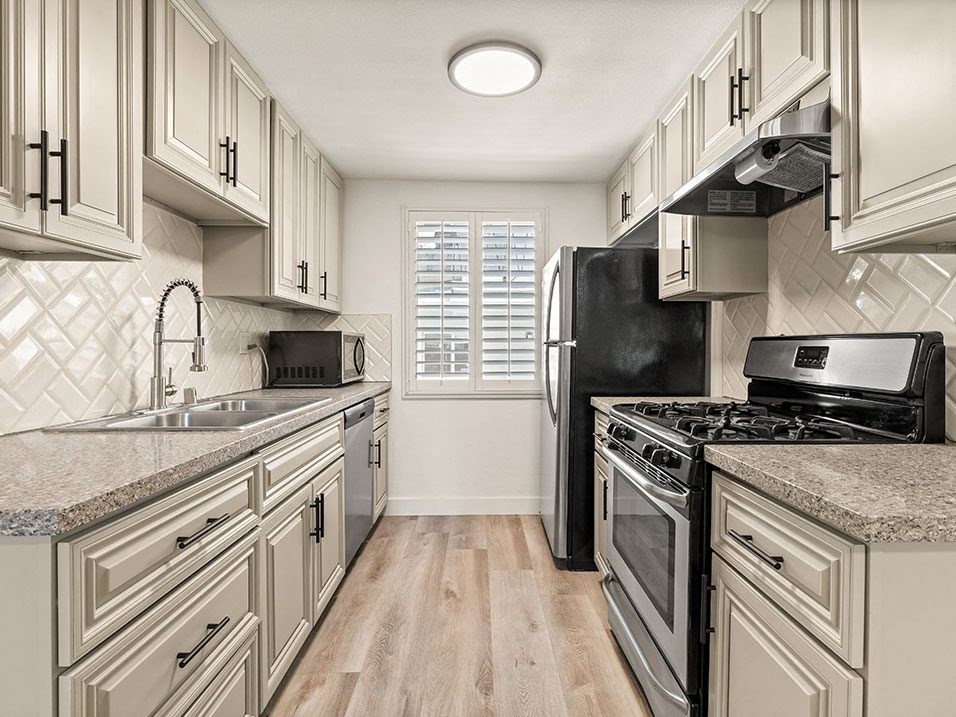 Tiled kitchen with stainless steel microwave, oven, fridge, and fixtures.