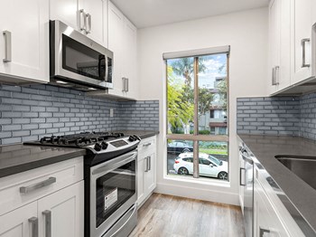 Blue tiled kitchen with stainless steel microwave, oven, and fixtures. Blue tiled kitchen with stainless steel microwave, oven, and fixtures. - Photo Gallery 3