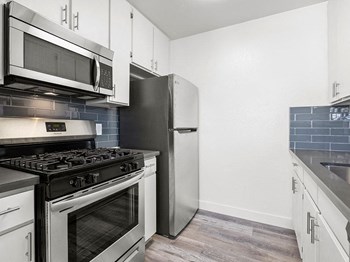 Blue tiled kitchen with stainless steel oven, microwave, and fridge. Blue tiled kitchen with stainless steel oven, microwave, and fridge. - Photo Gallery 2