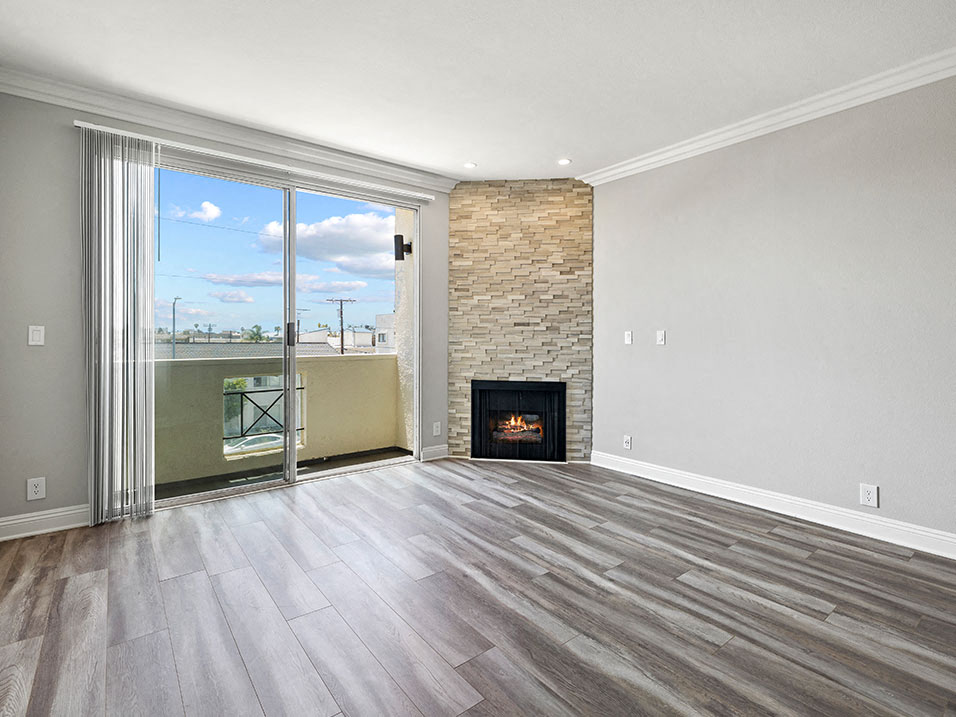 Hardwood floored living room with stone walled fireplace and balcony.