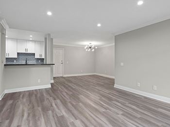 Living room with hardwood floors, can lights, and Edison light fixture.