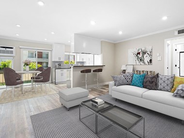 Hardwood floored living room with view of dining room, bar seating in kitchen, and balcony.