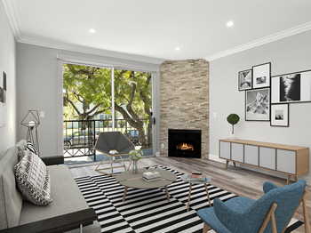 Hardwood floored living room with balcony access and stone walled fireplace.