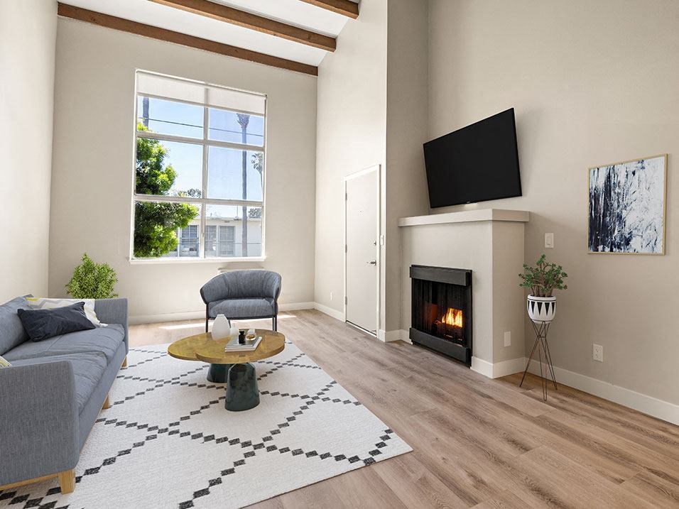 Hardwood floored living room with fireplace and large window to outdoors.