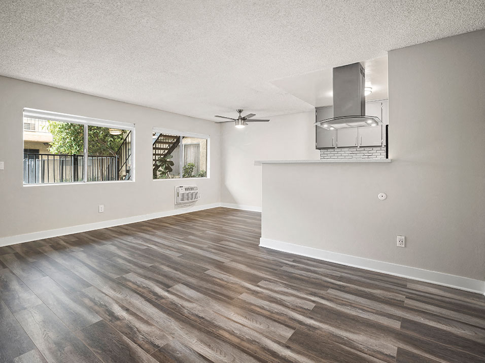 Large hardwood floored living room with ceiling fan over dining room.