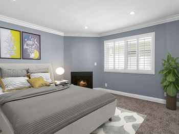 A bedroom with a grey bed and a fireplace.