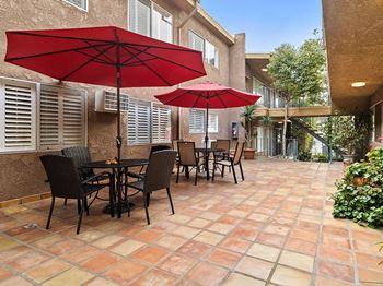 A patio with a table and chairs under a red umbrella.
