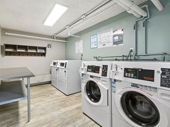 A laundromat with a washer and dryer on the right and a table on the left.
