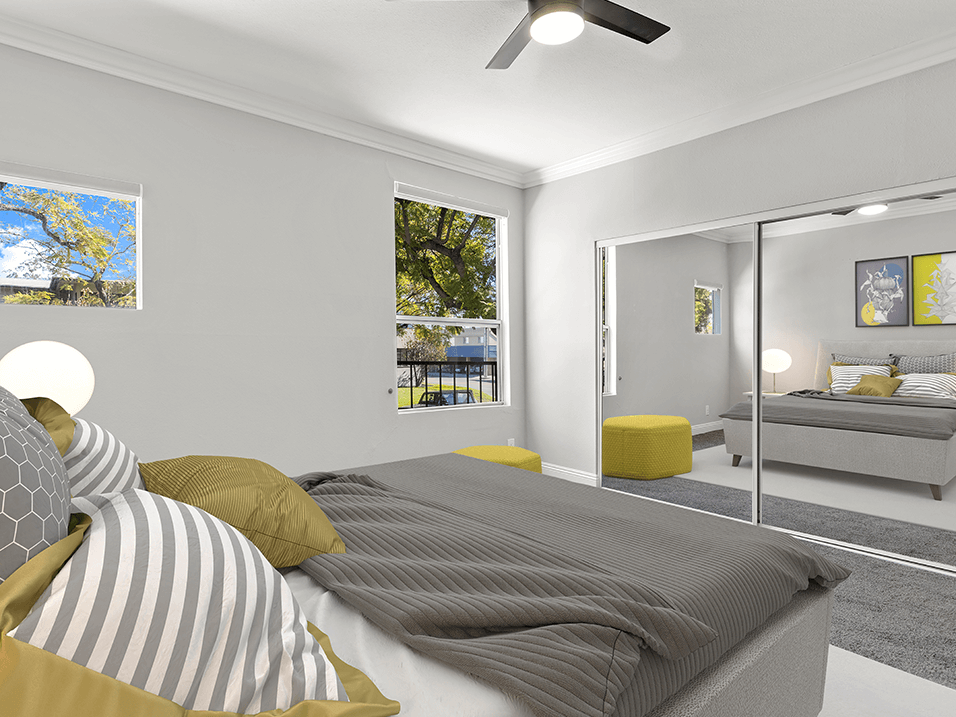 Carpeted bedroom with ceiling fan and mirrored closet.